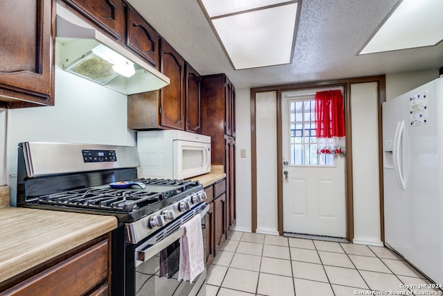 kitchen featuring light tile patterned floors, white appliances, a textured ceiling, and dark brown cabinetry