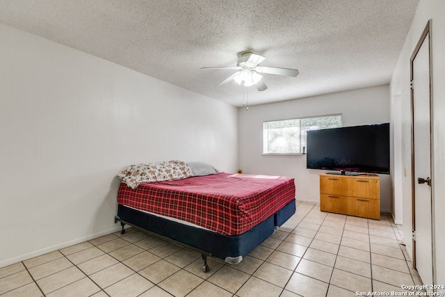 tiled bedroom with ceiling fan and a textured ceiling