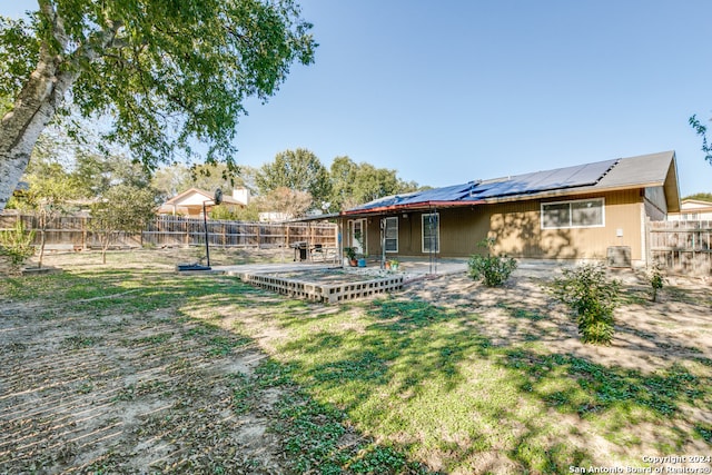 back of house with a patio area, a yard, and solar panels