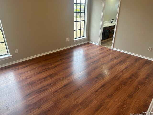 empty room featuring a wealth of natural light and dark wood-type flooring