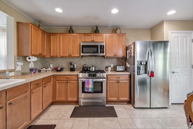 kitchen with appliances with stainless steel finishes, backsplash, light tile patterned floors, and sink