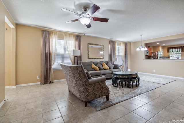 living room featuring a textured ceiling, plenty of natural light, light tile patterned flooring, and ceiling fan with notable chandelier