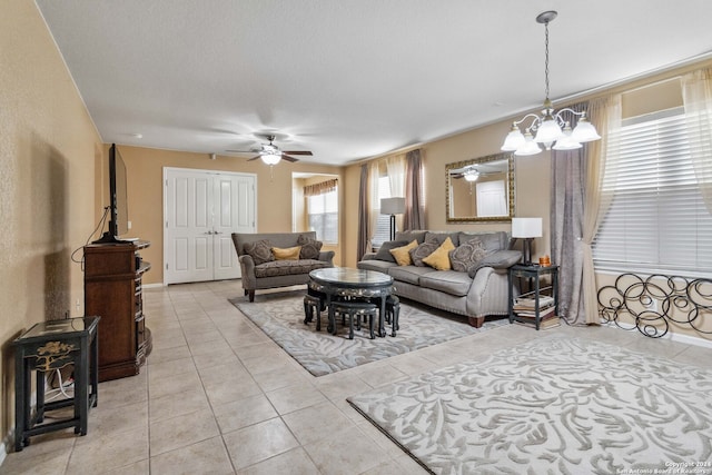 tiled living room featuring ceiling fan with notable chandelier and a textured ceiling