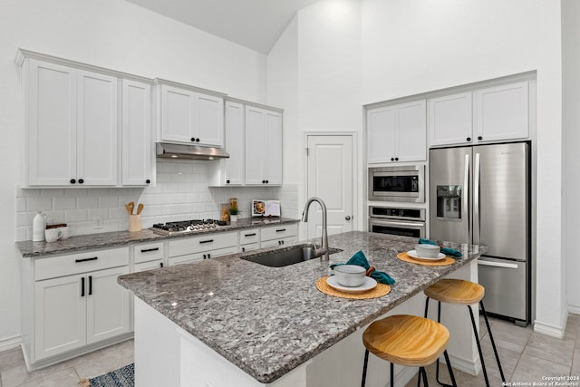 kitchen with a center island with sink, sink, stainless steel appliances, and tasteful backsplash