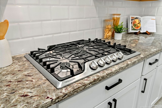 details with white cabinetry, light stone counters, and stainless steel gas cooktop