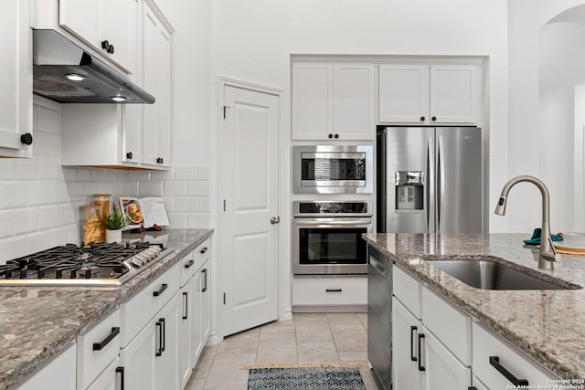 kitchen featuring white cabinets, appliances with stainless steel finishes, light stone counters, and sink