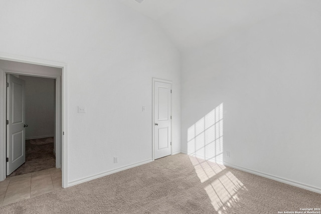 spare room featuring light carpet and high vaulted ceiling