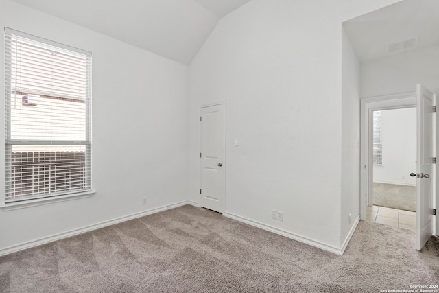 spare room with light colored carpet and vaulted ceiling