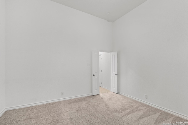 carpeted spare room with high vaulted ceiling