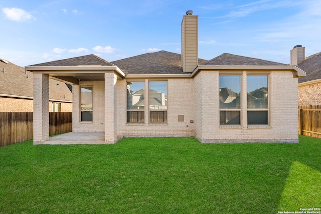 rear view of house featuring a lawn and a patio