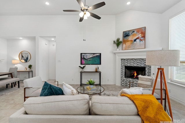 living room featuring plenty of natural light, ceiling fan, vaulted ceiling, and a tiled fireplace