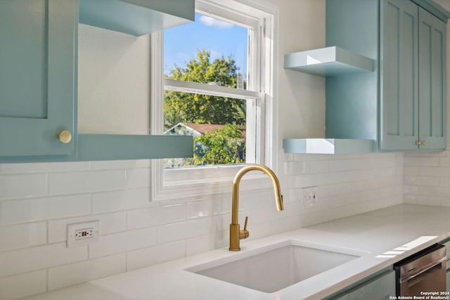 kitchen with stainless steel dishwasher, green cabinets, sink, and backsplash