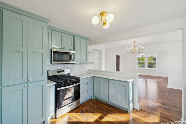 kitchen with appliances with stainless steel finishes, dark hardwood / wood-style flooring, a chandelier, hanging light fixtures, and kitchen peninsula