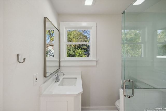 bathroom featuring vanity, toilet, and a shower with door