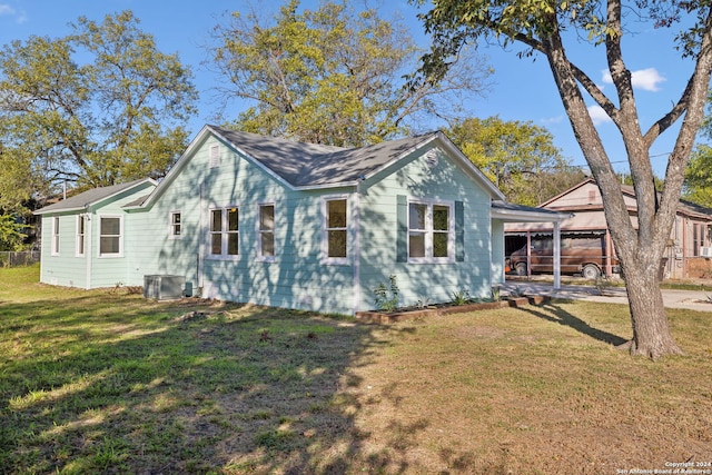 view of side of property with a lawn, a carport, and central air condition unit