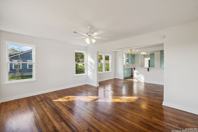 unfurnished living room with ceiling fan with notable chandelier and dark hardwood / wood-style floors