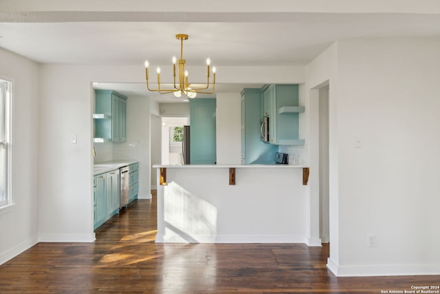 kitchen featuring stainless steel appliances, green cabinets, an inviting chandelier, and decorative backsplash