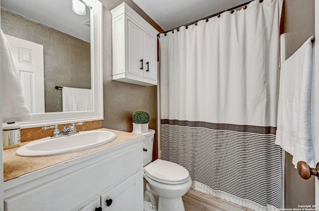 bathroom featuring hardwood / wood-style floors, vanity, toilet, and a textured ceiling