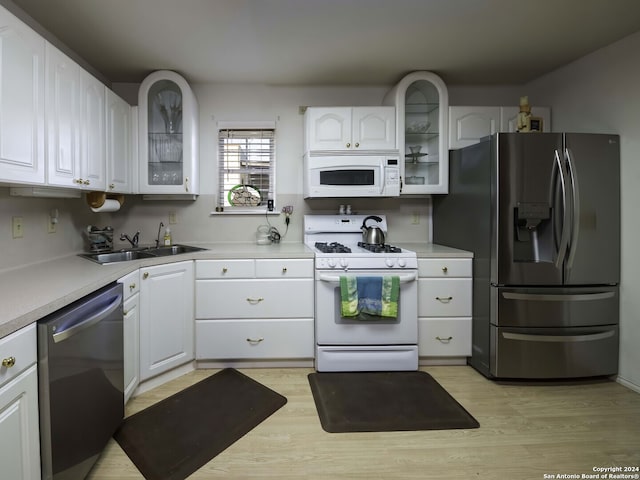 kitchen with appliances with stainless steel finishes, light hardwood / wood-style flooring, white cabinetry, and sink