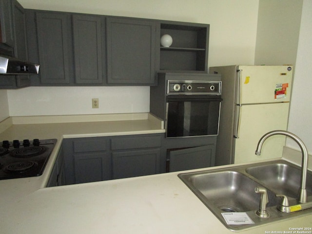 kitchen with stovetop, white refrigerator, oven, and sink