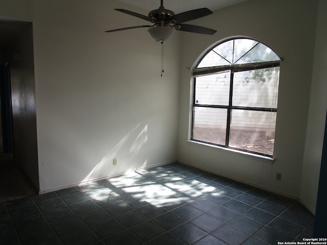 tiled spare room featuring ceiling fan