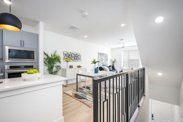 interior space with ceiling fan, hanging light fixtures, appliances with stainless steel finishes, and light hardwood / wood-style flooring