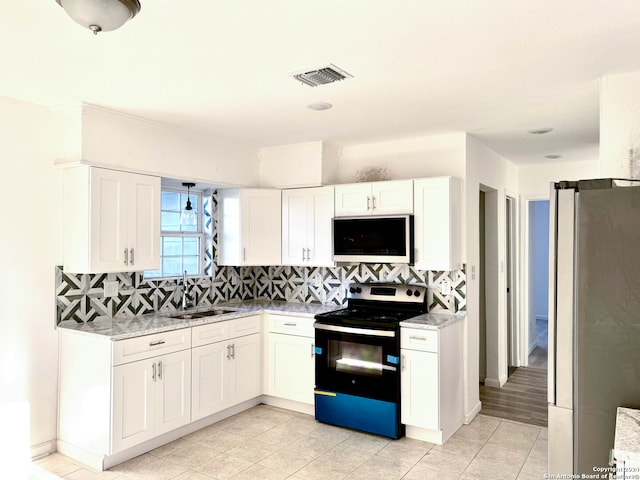 kitchen featuring light stone countertops, appliances with stainless steel finishes, tasteful backsplash, sink, and white cabinets