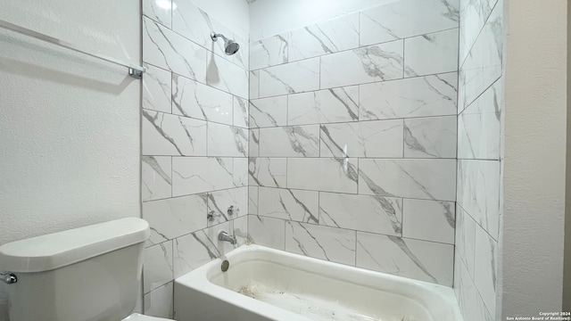 bathroom featuring tiled shower / bath combo and toilet