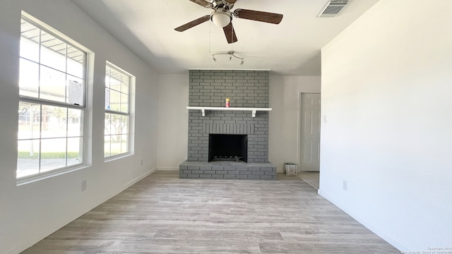 unfurnished living room with ceiling fan, a fireplace, and light wood-type flooring