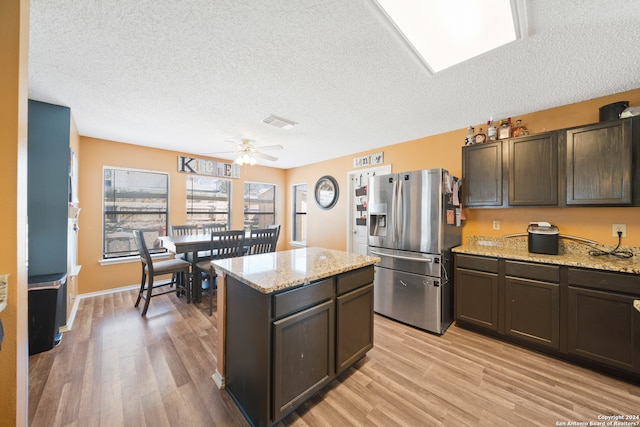 kitchen featuring dark brown cabinets, ceiling fan, light stone countertops, and stainless steel fridge with ice dispenser