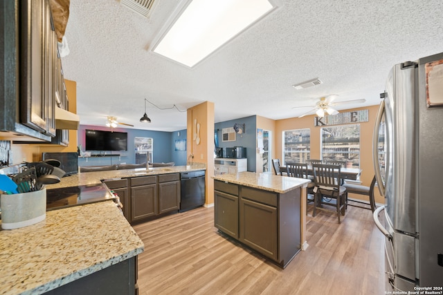 kitchen featuring a center island, a textured ceiling, black dishwasher, kitchen peninsula, and stainless steel refrigerator