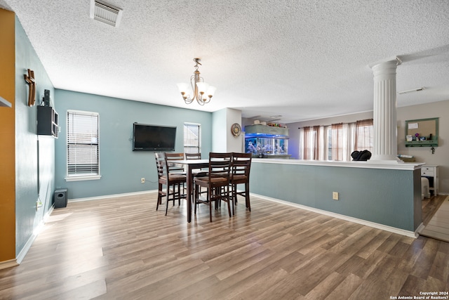 dining space featuring ornate columns, hardwood / wood-style flooring, and an inviting chandelier