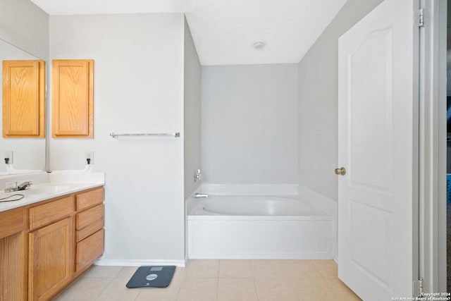 bathroom with a textured ceiling, vanity, a tub, and tile patterned flooring