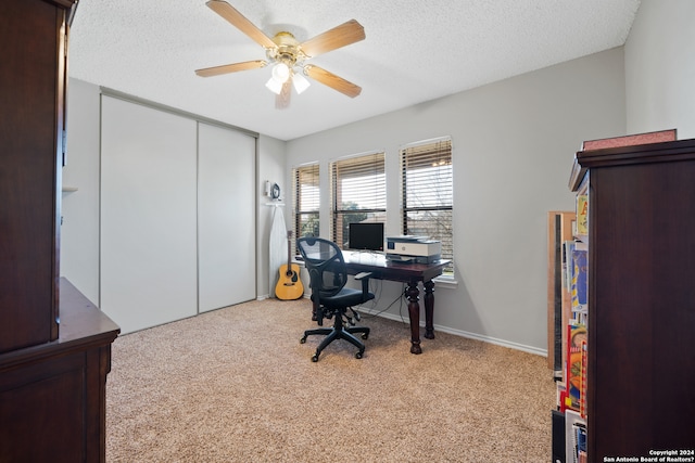 office area featuring a textured ceiling, light colored carpet, and ceiling fan