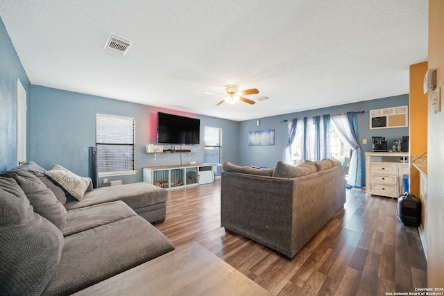 living room featuring plenty of natural light, ceiling fan, dark hardwood / wood-style flooring, and a textured ceiling