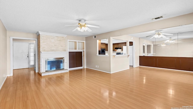 unfurnished living room featuring a large fireplace, light wood-type flooring, and a textured ceiling