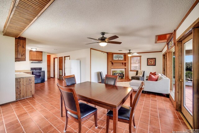 tiled dining space with ceiling fan, crown molding, and a textured ceiling