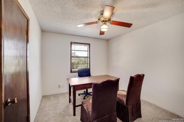 carpeted office space featuring a textured ceiling and ceiling fan