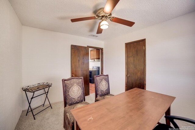 dining area featuring a textured ceiling, light colored carpet, and ceiling fan