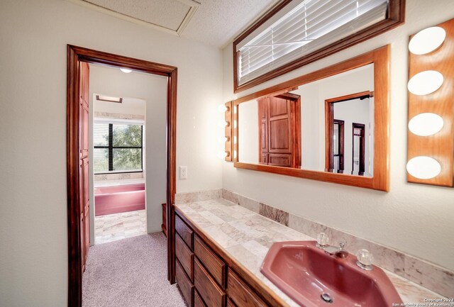 bathroom with vanity, a tub to relax in, and a textured ceiling