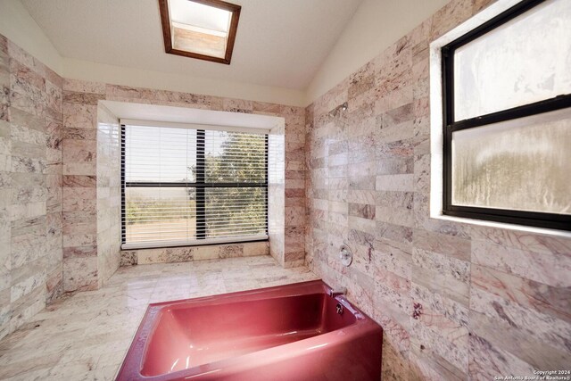 bathroom with a tub to relax in, tile walls, and lofted ceiling