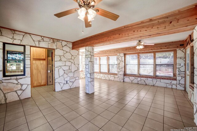 unfurnished room featuring beam ceiling and light tile patterned flooring