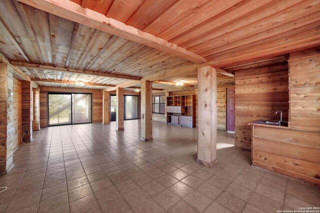 tiled empty room with wooden ceiling, sink, and wooden walls