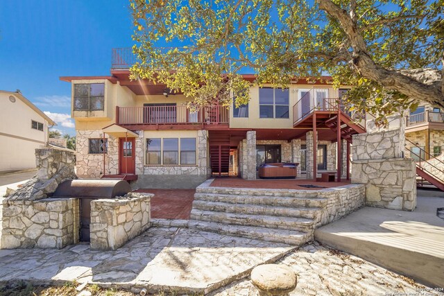 view of front of property featuring a patio area, a balcony, and a hot tub