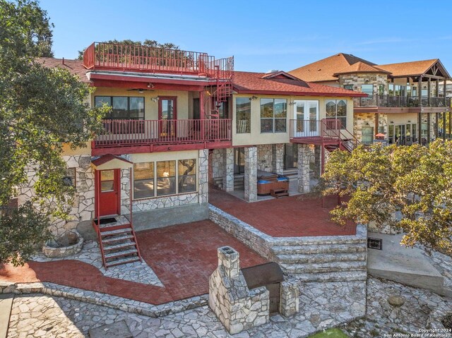 back of house featuring a patio area, a balcony, and a hot tub