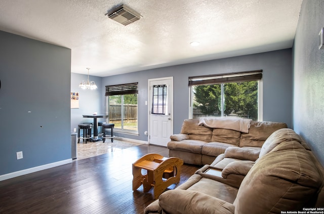 living room with a textured ceiling, hardwood / wood-style flooring, and an inviting chandelier