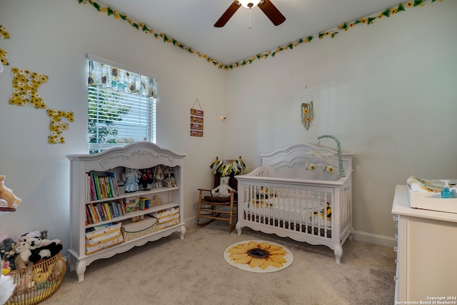 carpeted bedroom featuring ceiling fan and a nursery area