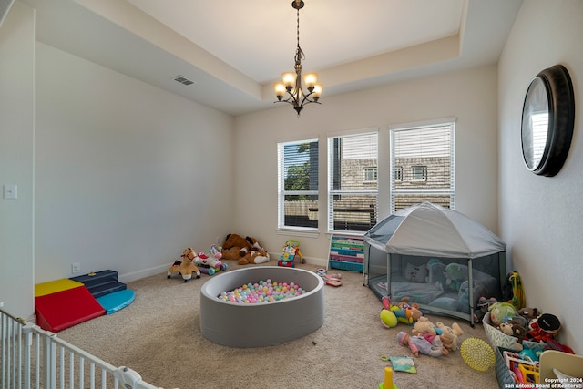 recreation room featuring a raised ceiling, carpet floors, and a chandelier