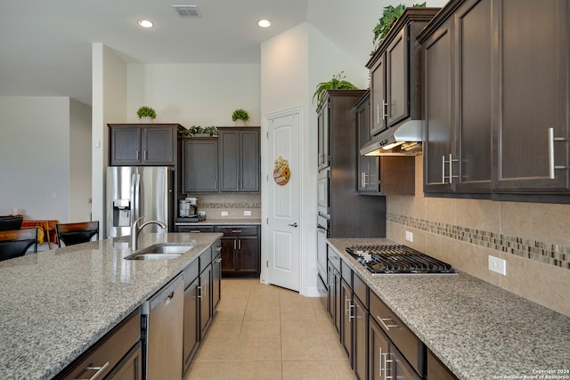 kitchen with backsplash, light stone countertops, sink, and appliances with stainless steel finishes