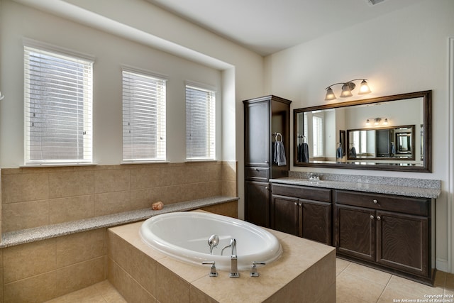 bathroom with tile patterned flooring, vanity, a healthy amount of sunlight, and tiled bath